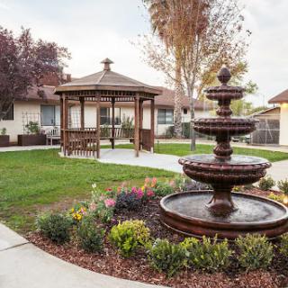 A serene garden featuring a charming gazebo and a decorative fountain, surrounded by vibrant flowers and manicured lawns.
