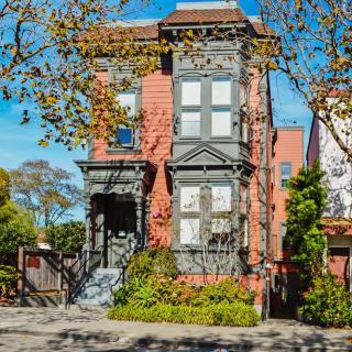 A historic Victorian house surrounded by autumn trees.