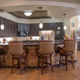 A modern kitchen featuring a large countertop with bar stools and pendant lights.