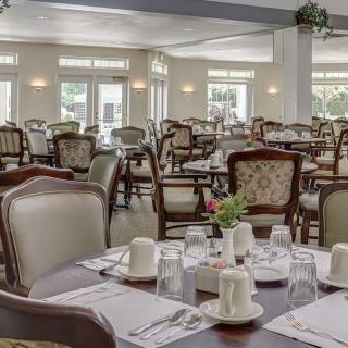 An elegant dining room with neatly set tables and classic chairs.