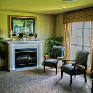 A cozy living room corner featuring a fireplace, two chairs, and decorative elements.