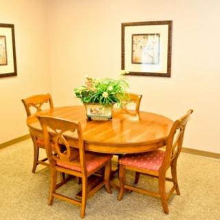 A cozy dining room with a round wooden table surrounded by four chairs, decorated with a potted plant and framed artwork on the walls.