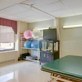 A rehabilitation room with exercise equipment and a treatment table.