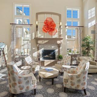 A modern living room with stylish furniture and a fireplace, illuminated by natural light from large windows.