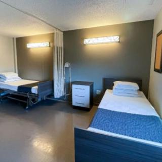 A hospital room with two beds and minimal furnishings.