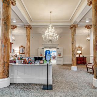 A luxurious hotel lobby featuring a grand chandelier and ornate pillars.