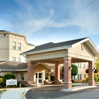 A modern building entrance with a covered driveway and clear skies above.