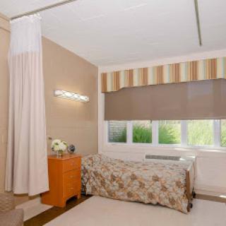 A cozy and well-lit bedroom featuring soft curtains and a floral bedspread.
