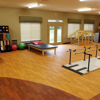 A spacious rehabilitation room equipped with various physical therapy tools and exercise equipment.