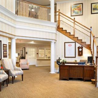 A welcoming lobby area with a wooden staircase, a desk, and seating arrangements.