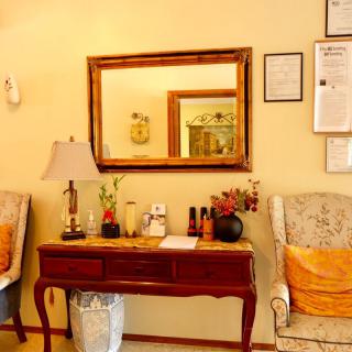 A cozy room featuring a wooden console table with decorative items, a large mirror, and two upholstered chairs.