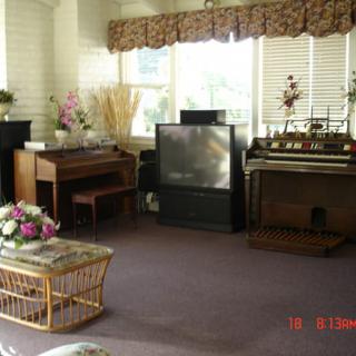A cozy living room featuring a piano, organ, and a large television.