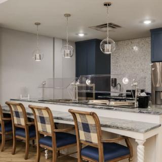A modern kitchen featuring a marble countertop with bar stools and stylish pendant lighting.