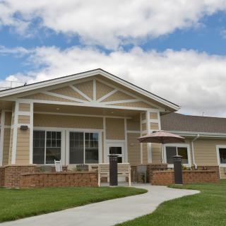 A suburban house with a neatly manicured lawn and a brick facade, under a partly cloudy sky.