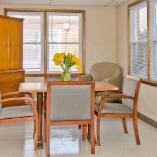 A cozy dining area featuring a wooden table, chairs, and a vibrant bouquet of flowers.