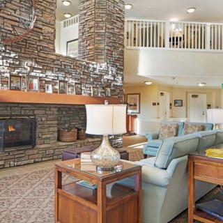 A cozy living room featuring a stone fireplace, comfortable seating, and warm lighting in an open-concept space.
