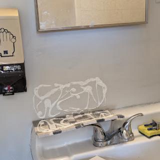 A bathroom sink area featuring a mirror, soap dispenser, and hand washing instructions.