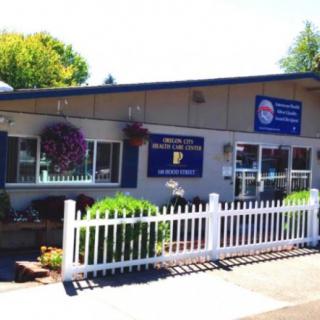 An exterior view of a roadside restaurant with a white picket fence and hanging flower baskets.