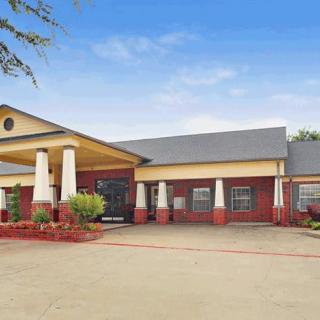 A front view of a single-story hotel with columns and a welcoming entrance.