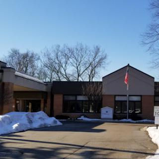 A winter view of a modern building with a flag, surrounded by snow under a clear blue sky.