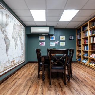 A cozy library study room with a large world map and wooden furniture.