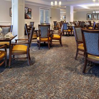 An empty restaurant dining area with neatly arranged tables and chairs on a carpeted floor.
