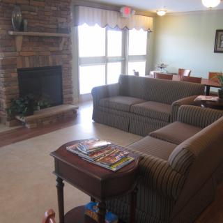 A cozy living room featuring a brick fireplace, comfortable sofas, and a side table with magazines.