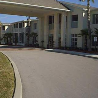 Entrance of a hotel or resort with a driveway and palm trees.
