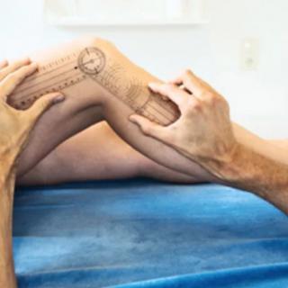 A physiotherapist uses a goniometer to measure knee range of motion during an examination.