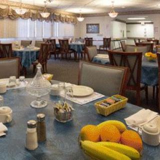 A cozy dining area set for breakfast, featuring tables adorned with plates, cutlery, and fresh fruit.