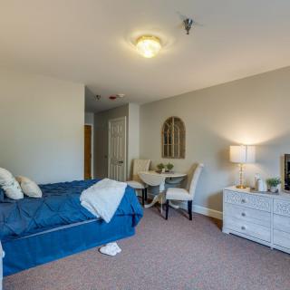 A cozy bedroom with a bed, small dining table, chairs, and a lamp.