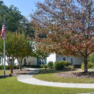 A scenic view of a building surrounded by trees with an American flag and a curved pathway.