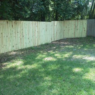 A backyard with a wooden fence and a well-maintained lawn.