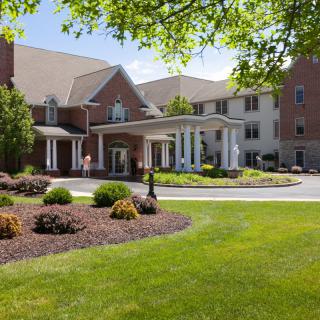 A well-maintained building entrance with landscaped surroundings and a circular driveway.