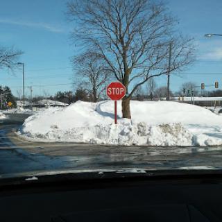 A stop sign near a snow-covered area with a clear blue sky.