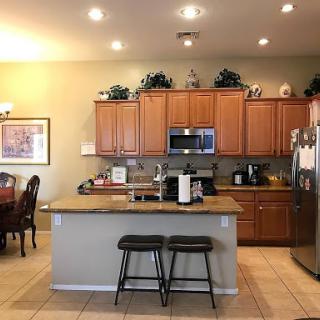 A modern kitchen featuring wooden cabinets, a spacious countertop, and bar stools for casual dining.