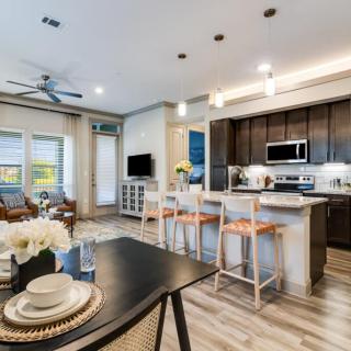 A modern open-concept living room and kitchen space with neutral color tones and contemporary furnishings.