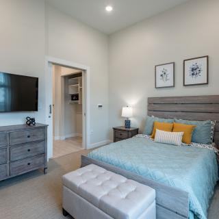 A modern bedroom with contemporary decor, featuring a comfortable bed, wall-mounted television, and stylish furniture.