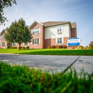 A residential apartment building with a well-maintained lawn and sidewalk.