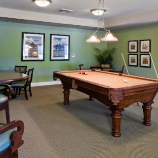 A spacious recreation room featuring a classic pool table, set against stylish green walls and elegant decor.