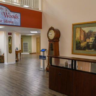A spacious lobby area with a large clock, a painting, and wooden flooring.
