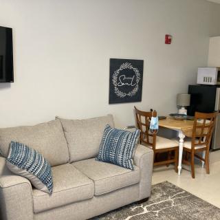 A cozy living room with a couch, wall-mounted TV, and a small dining area.