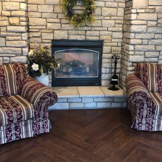 A cozy living room setup with a brick fireplace and patterned chairs.