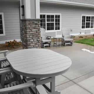 A cozy outdoor seating area featuring a gray table and chairs next to a residential building.
