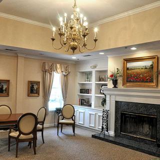 A cozy living room with a chandelier, featuring a fireplace, artwork, and elegant furniture.