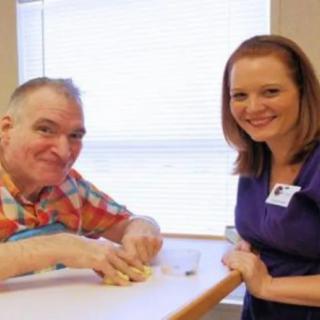 A man and a woman smiling while interacting at a table indoors.