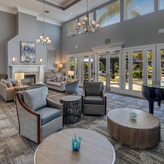 A spacious and modern living room with high ceilings, featuring elegant furniture, a fireplace, and large windows allowing natural light to fill the space.