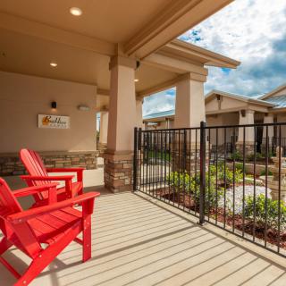 A cozy patio area with red chairs and a fenced garden view.