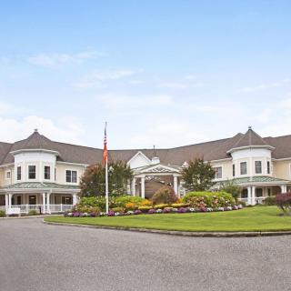 A large, elegant building with a circular driveway and landscaped gardens at the entrance.