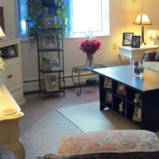 A cozy living room with warm lighting, featuring a coffee table, decorative lamps, and framed pictures.